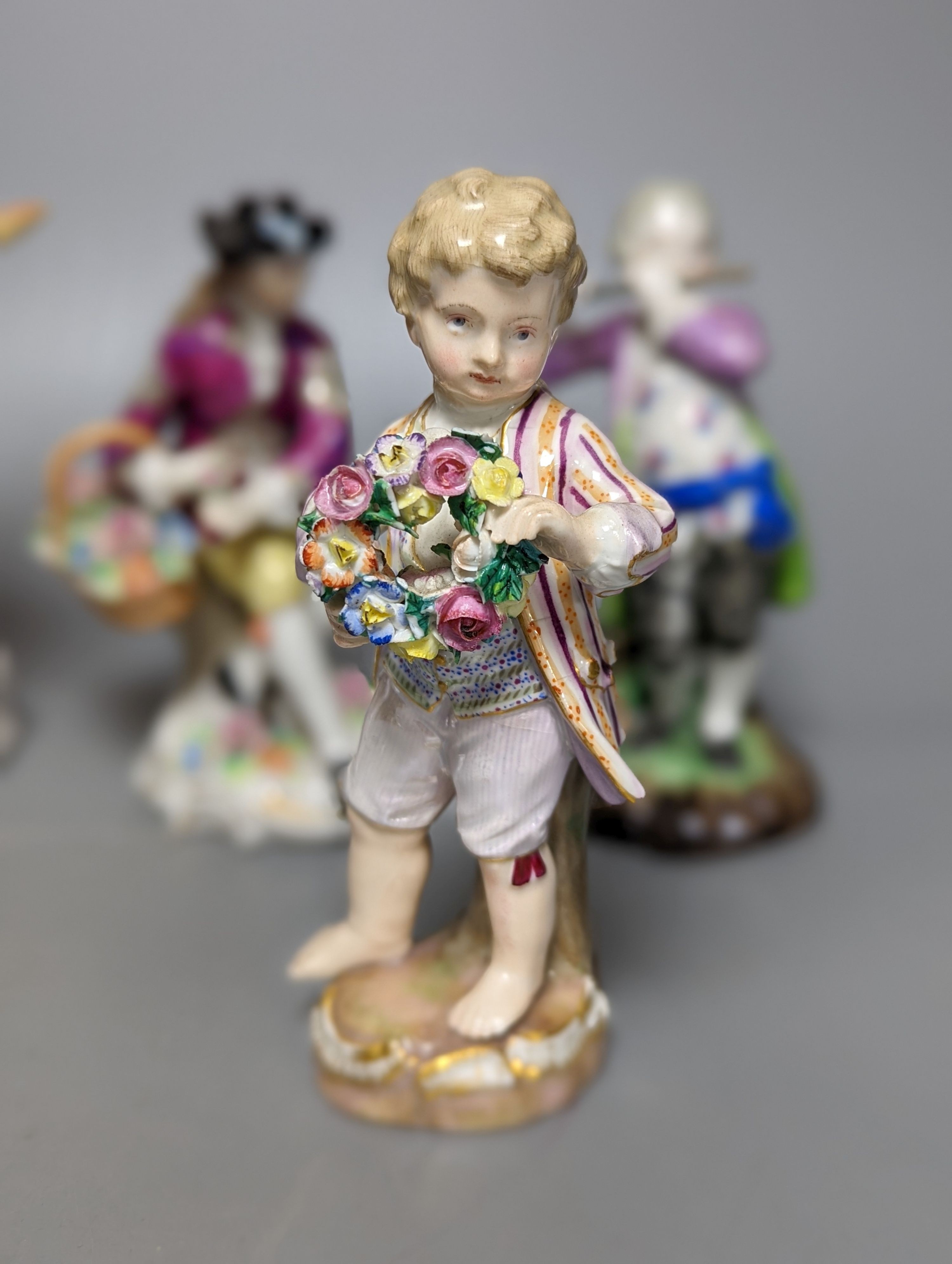 A late 19th century Meissen figure of a boy holding a garland of flowers, and a Sampson Hancock Derby figure and three other continental porcelain figures, tallest 18 cms high.